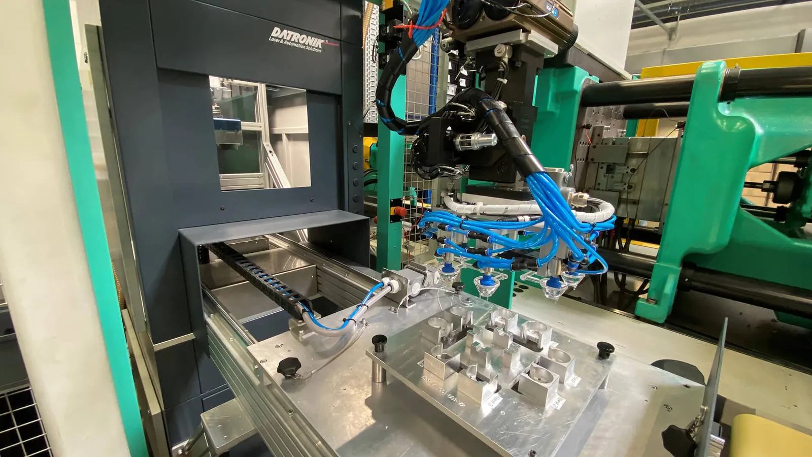 DATRONIK Laser-Automationszelle an der Spritzgussmaschine mit Roboter-Handling von Kunststoffoptiken bei VIAOPTIC